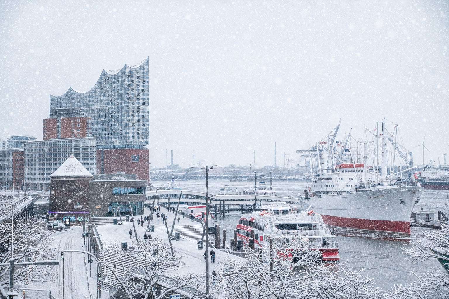 Winterliches Hamburg mit Elbphilharmonie und Hafen im Schnee.